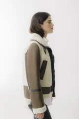 Campera tipo gamulán de cuero negro con interior y detalles en piel sintética negra, cierre frontal y cuello con hebillas ajustables.