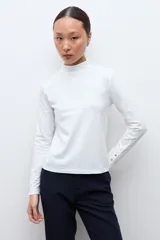 Media polera de manga larga con cuello alto y detalle de frunces en los puños, confeccionada en tejido suave y elástico.