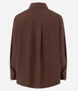 Camisa de corte oversized con estilo sastre, confeccionada en tejido plano. Presenta cuello clásico, cierre frontal con botones, mangas largas con puños anchos y sisas desplazadas.