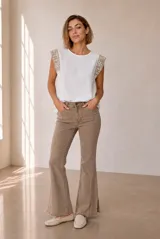 Blusa blanca sin mangas, confeccionada en lino, con detalles de crochet en los hombros.