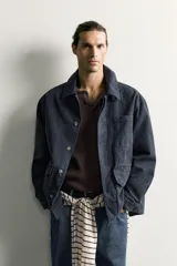 Sobrecamisa regular fit confeccionada en tejido de algodón negro con estructura canvas. Tiene cuello solapa, manga larga con puño abotonado, bolsillos de plastrón con solapa en la cadera y un bolsillo en el pecho. Cierre frontal con botones ocultos bajo solapa.