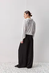 Pantalón wide leg de tiro medio y calce amplio, color marrón, con pinzas delanteras, cierre frontal y bolsillos laterales funcionales.