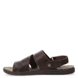 Sandalias de cuero vacuno color marrón habana, con diseño de tiras anchas cruzadas y ajuste mediante velcro en el talón. Presenta detalle de marca grabado en una etiqueta de cuero y suela de goma ergonómica.