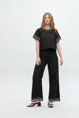 Blusa blanca de manga corta con cuello redondo y bordado de lentejuelas y mostacillas plateadas en el cuello y las mangas.