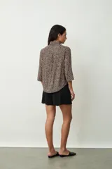 Camisa de manga tres cuartos con estampado de leopardo en tonos beige y negro, cuello camisero y botones frontales.