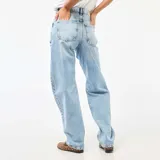 Pantalón jean de corte globo y tiro alto, en tono azul claro con efecto lavado. Presenta diseño amplio de perneras curvas y costuras decorativas.