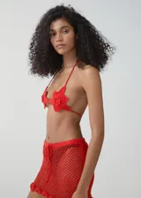 Top de bikini estilo halter confeccionado en tejido de crochet color rojo, con diseño de flores en las copas y cierre de lazo en la espalda.