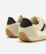 Championes estilo runner de diseño vintage, confeccionados en una combinación de tejido de malla respirable, recortes de gamuza y detalles en material sintético. Presentan cierre con cordones, detalle lateral aplicado en contraste y suela de goma plana con base color caramelo.