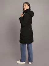 Campera Calvin Klein tipo walker acolchada y de acabado mate color negro, con diseño largo, mangas largas, cierre frontal con cremallera y bolsillos laterales con cierre. Incluye capucha con forro de sherpa interior.