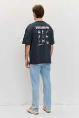 Remera de corte oversize color blanco tiza, de manga corta y cuello redondo, con pequeño estampado gráfico azul en el pecho.