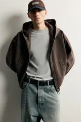 Cazadora de denim de algodón color negro con efecto lavado, de corte relaxed fit, manga larga y capucha. Cuenta con cierre frontal de cremallera, bolsillos frontales tipo canguro y acabados con elástico en puños y cintura.