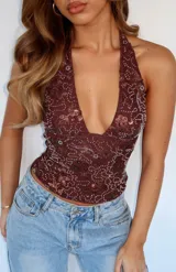 Top marrón con escote halter y espalda descubierta, con apliques de lentejuelas plateadas y doradas.