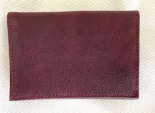 Tarjetero de cuero vacuno color bordó con costuras rojas. Tiene seis ranuras para tarjetas.