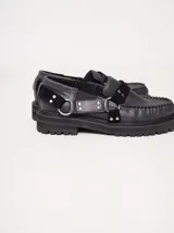 Mocasines de cuero negro con plataforma, diseño tipo náutico con costuras reforzadas en la puntera, detalle de tira sobre el empeine con apliques metálicos y argollas laterales.