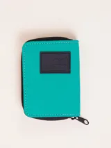 Billetera de nylon color verde esmeralda con cierre perimetral y parche de goma negro con logo grabado en el frente.