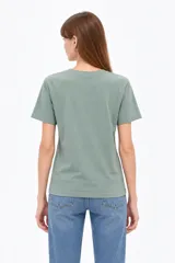 Remera de manga corta color verde militar, con cuello redondo y diseño holgado. Presenta estampado frontal con ositos y texto con detalles de glitter.
