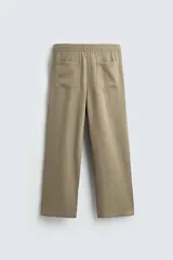 Pantalón negro de corte relajado con cintura elástica ajustable y pliegues en la parte delantera. Presenta bolsillos laterales y bolsillos traseros de parche.