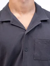 Camisa de manga corta color beige, confeccionada en tejido piqué de algodón, con cuello cubano y un bolsillo de parche en el pecho.