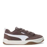 Championes Puma de estilo urbano inspirados en el skate, con perfil bajo. Presentan una estructura combinada de material sintético y superposiciones de gamuza en color negro, con el icónico logo de la marca en blanco en el lateral. Cuentan con cordones gruesos en color crema, entresuela blanca y suela de goma color caramelo.