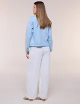 Campera de denim liviano azul, de corte clásico y silueta recta, con cuello camisero, cierre frontal con botones rústicos y bolsillos con solapa en el pecho.