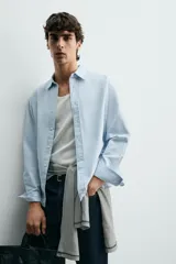 Camisa regular fit de color celeste, confeccionada en tejido con mezcla de algodón y seda, con cuello solapa, manga larga con puño abotonado y cierre frontal de botonadura.