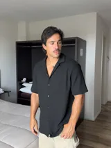 Camisa negra de manga corta, con cuello tipo solapa y textura de punto.