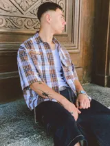 Camisa de manga corta con corte híbrido boxy fit/oversize, confeccionada en algodón. Disponible en tres diseños: a cuadros marrones, a rayas blancas y negras, y a rayas burdeos y blancas. Presenta bordados de diseño propio de la marca.