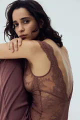 Body de encaje color marrón, con escote en V pronunciado y breteles anchos con detalle de encaje festoneado. Presenta copas sin forro ni aros y un refuerzo interior con botones a presión ocultos en la parte inferior.