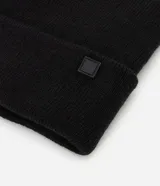 Gorro de punto de estilo beanie, color bordó, con borde plegado y etiqueta decorativa aplicada.