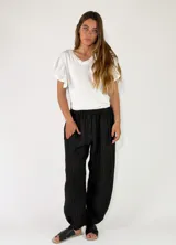 Pantalón de lino azul marino con diseño de rayas diplomáticas verticales claras, corte holgado y cintura elástica fruncida.