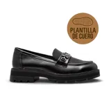 Zapato tipo mocasín de estilo casual, confeccionado en cuero negro con acabado liso y detalles en textura gamuzada en la parte superior. Presenta una suela track robusta y un detalle metálico decorativo en el empeine.