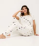 Pantalón de pijama estilo jogger con estampa de corazones en tonos suaves. Presenta cintura elástica con cordón ajustable y detalle de friso lateral, confeccionado en tejido peach touch de tacto suave.