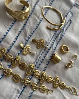 Pulsera de diseño artesanal elaborada eslabón por eslabón a mano, con eslabones circulares texturados de metal dorado y cadena regulable.