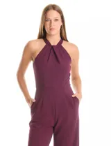 Enterito largo de crepe color rojo, con escote halter anudado y pierna ancha. Presenta bolsillos delanteros y abertura en la espalda con cierre invisible y botón.