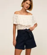 Short tipo mom de jean azul marino con cintura alta, bolsillos delanteros y cinturón ajustable confeccionado en la misma tela con pespuntes visibles.