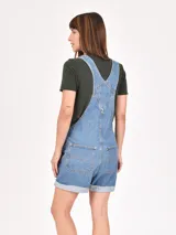 Monoprenda (jardinera) corta de denim color off-white, con tirantes ajustables y bolsillo frontal tipo pechera.