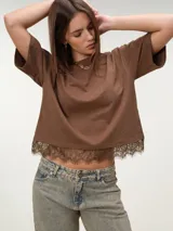 Remera boxy de manga corta marrón, de corte holgado y diseño liso, con detalle de encaje a tono en el borde inferior.