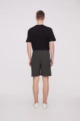 Bermuda de corte recto y diseño minimalista, confeccionada en tejido técnico de poliéster. Presenta cintura elástica con cierre de botón frontal, bolsillos laterales y un bolsillo pequeño adicional en el lateral izquierdo.