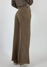 Pantalón de jean beige de corte acampanado con terminación desflecada.