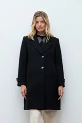 Tapado clásico de corte recto en color beige, con solapas, cierre frontal de botones y bolsillos laterales. Presenta un diseño minimalista y elegante.