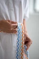 Vestido camisero corto color amarillo pálido con estampado floral en el hombro izquierdo y cinturón de tela con diseño geométrico.