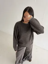 Sweater de punto color gris con cuello redondo, mangas largas y terminaciones con detalle de pespunte en color crudo en el cuello, puños y ruedo.
