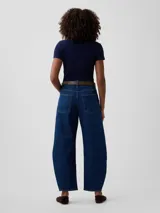 Jean de corte barrel y tiro alto, color azul oscuro, con diseño arqueado en las piernas y bolsillos laterales y traseros.