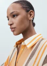 Camisa de lyocell con estampado de rayas verticales en tonos naranja, marrón y beige. Tiene cuello camisero, manga larga con puños abotonados y cierre frontal con botones.
