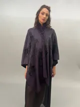 Ruana de lana merino tejida, teñida y estampada, con cuello plisado en fieltro de lana merino.