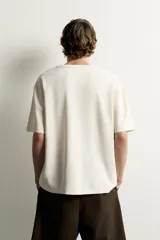 Remera de corte holgado color gris oscuro, con cuello redondo y mangas cortas. Confeccionada en tejido suave con mezcla de modal.