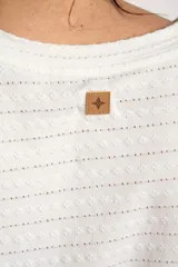Remera blanca de manga corta con cuello redondo y textura de líneas horizontales con perforaciones.