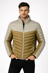 Campera acolchada de nylon con diseño color block. La parte superior del torso y los hombros son de color beige claro, mientras que el cuerpo principal y la parte inferior de las mangas son de color verde oliva. Posee cuello alto y cierre frontal.