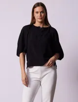 Blusa de gasa blanca con estampado de hojas en azul marino, cuello a la base con escote en V y botones, y mangas cortas abullonadas.