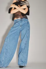 Jean de corte wide leg en color azul medio, con costuras verticales decorativas a lo largo de las piernas y diseño de tiro medio.